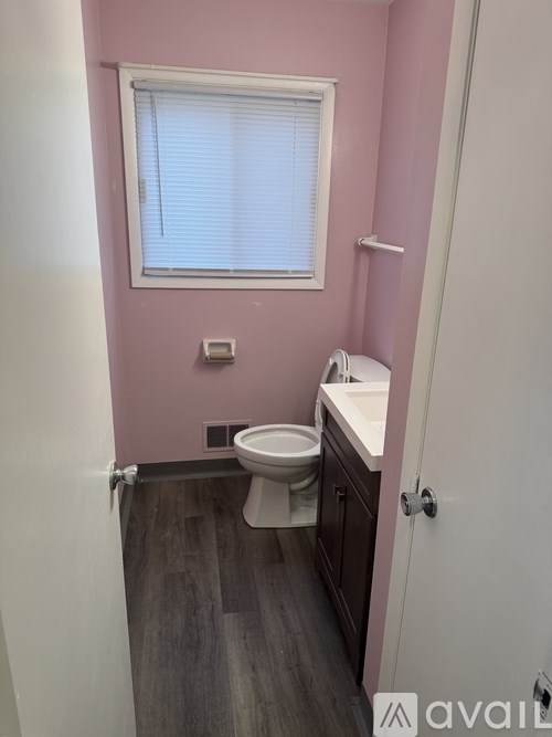 A bathroom with a toilet, sink, and window.