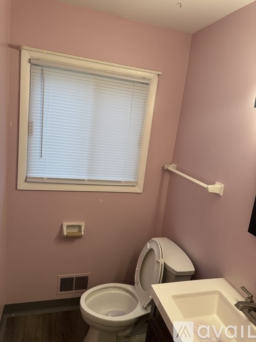 A bathroom with pink walls and a white toilet.
