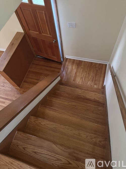 A wooden staircase with a white wall on the side.