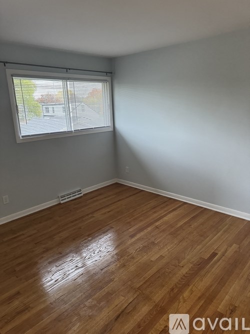 A room with wooden flooring and a window with blinds.