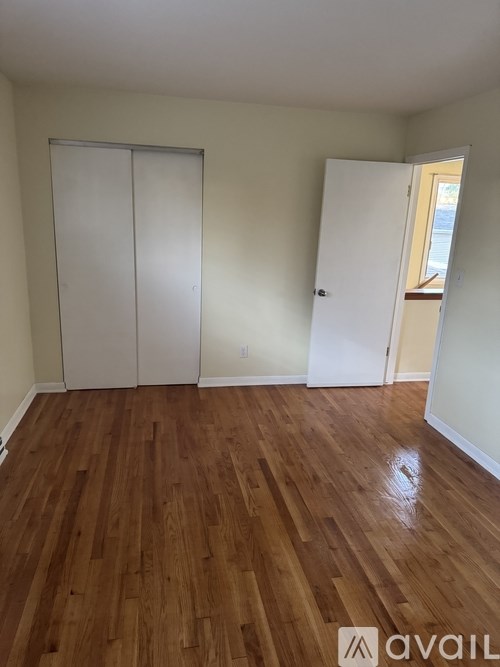 A room with wooden floors and two white closet doors.