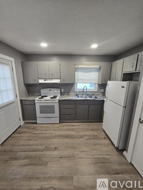 A kitchen with white appliances and grey cabinets.