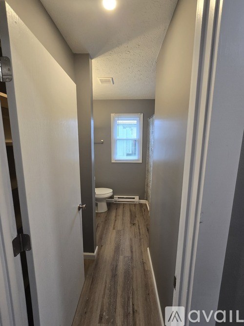 A narrow hallway with a toilet at the end.
