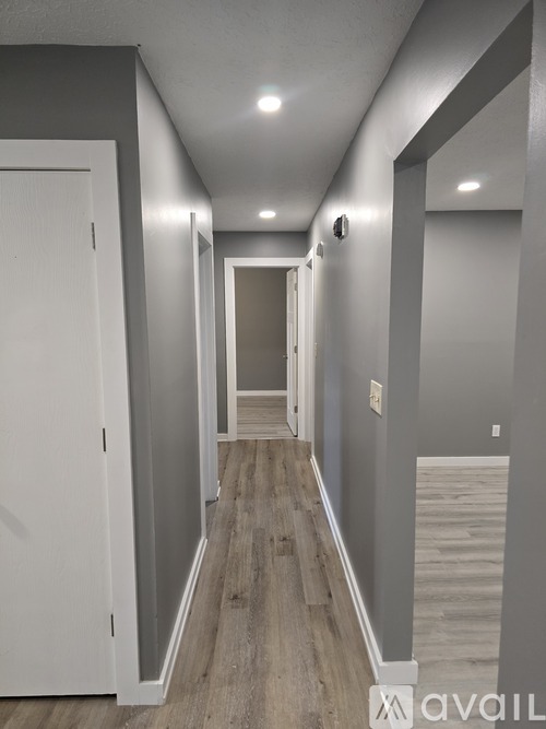 A long hallway with a white door on the left and a light on the wall on the right.