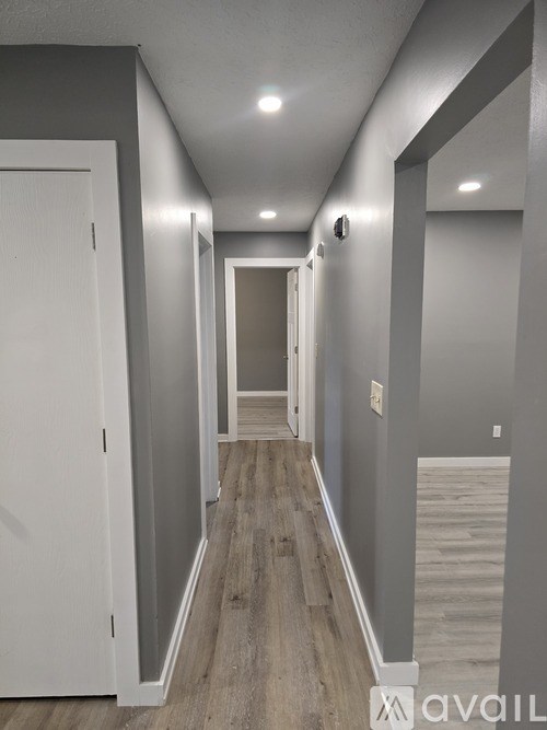 A long hallway with a white door on the left and a light on the wall on the right.