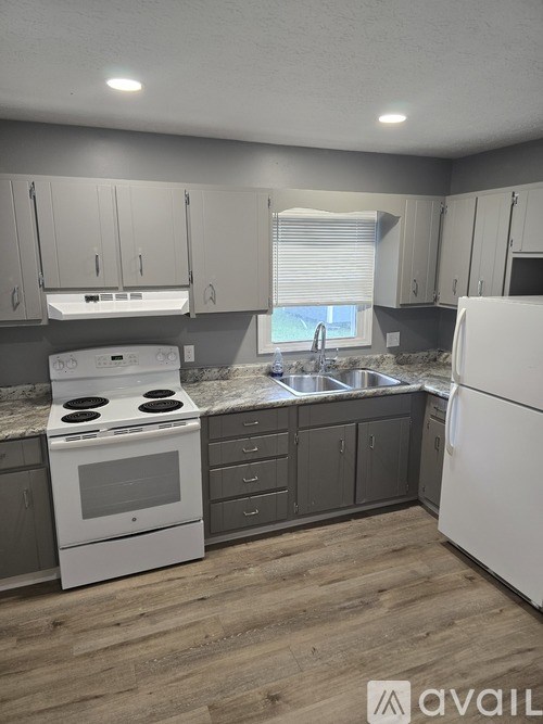 A kitchen with white appliances and wooden floors.