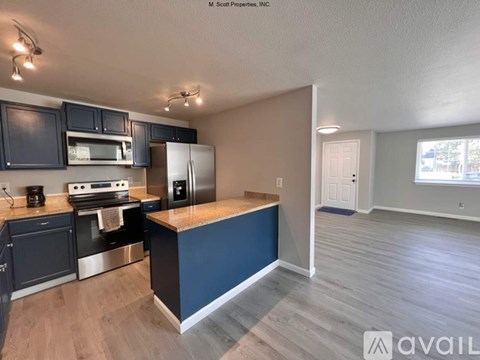 A kitchen with dark cabinets and a blue island.
