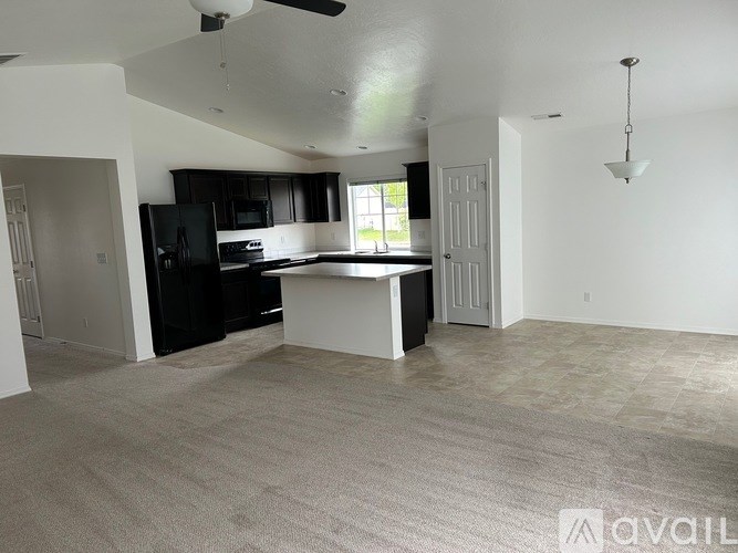 A spacious living room with a kitchen area in the background.