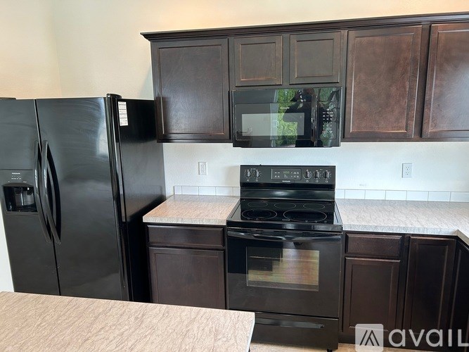 A black refrigerator and stove in a kitchen with brown cabinets.