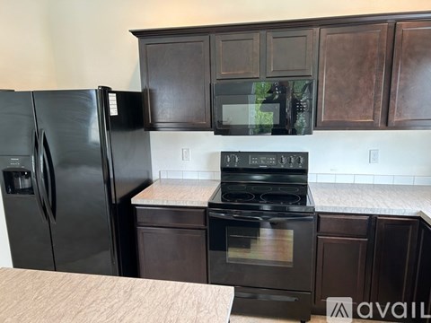 A black refrigerator and stove in a kitchen with brown cabinets.