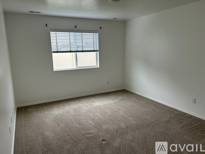 A room with a carpeted floor and a window with blinds.