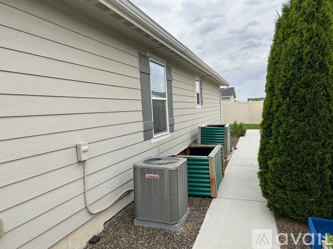 A grey air conditioning unit is outside a house.