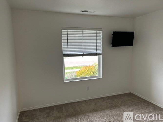A room with a window and a flat screen TV mounted on the wall.