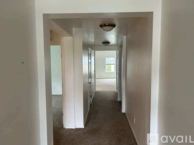 A long hallway with a carpeted floor and white walls.