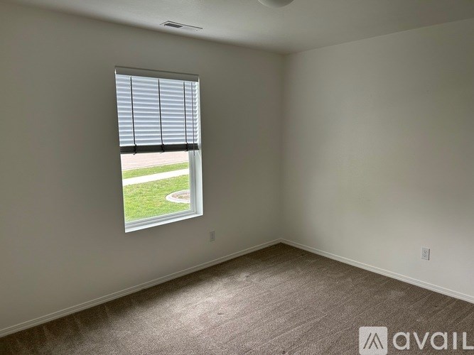 A room with a carpeted floor and a window showing a lawn outside.