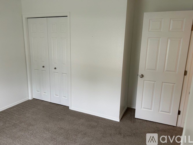 A carpeted room with two white doors.