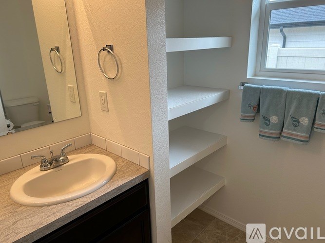 A bathroom with a sink, mirror, and towel rack.