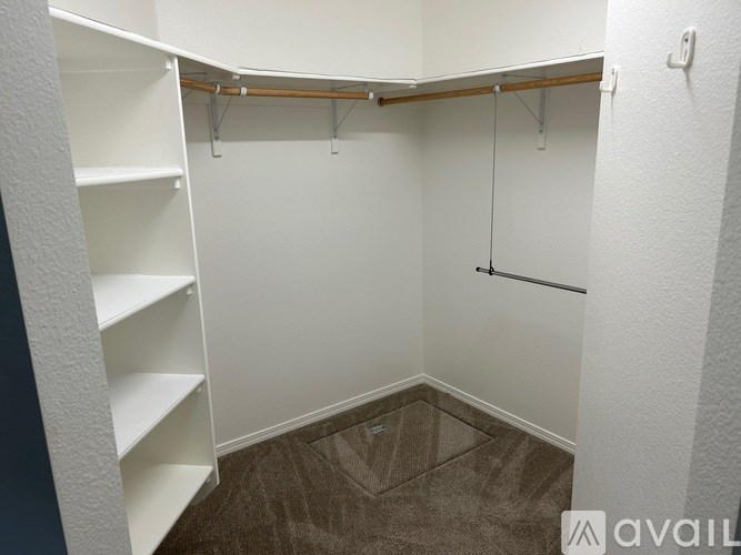 A walk-in closet with white shelves and a wooden rod.
