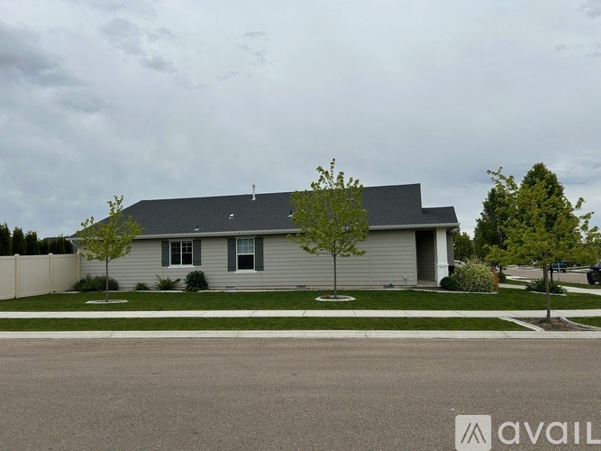 A house with a grey roof and a white fence is available for sale.