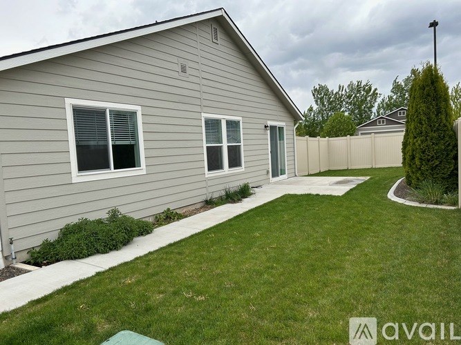 A house with a grey siding and a white window is for sale.