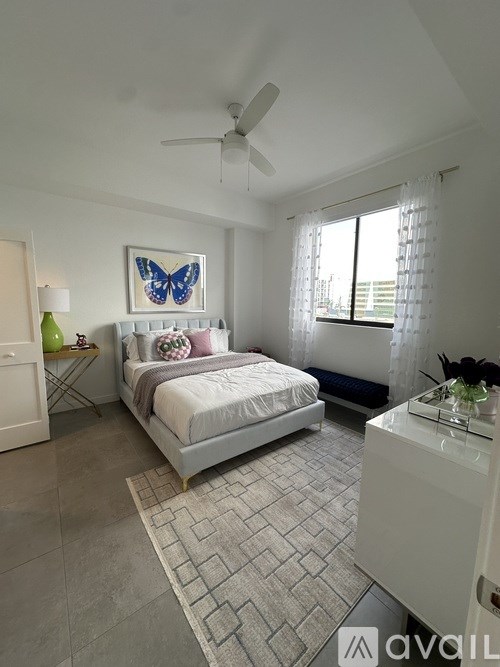 A bedroom with a bed, a ceiling fan, and a window with curtains.