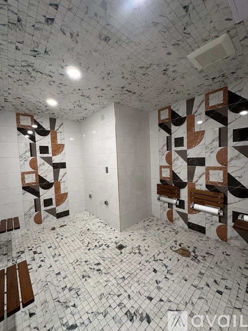 A bathroom with a mosaic floor and a wall with a design that looks like a broken mirror.