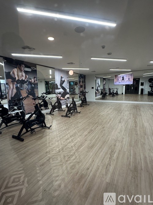 A gym with a variety of exercise equipment and a TV screen.