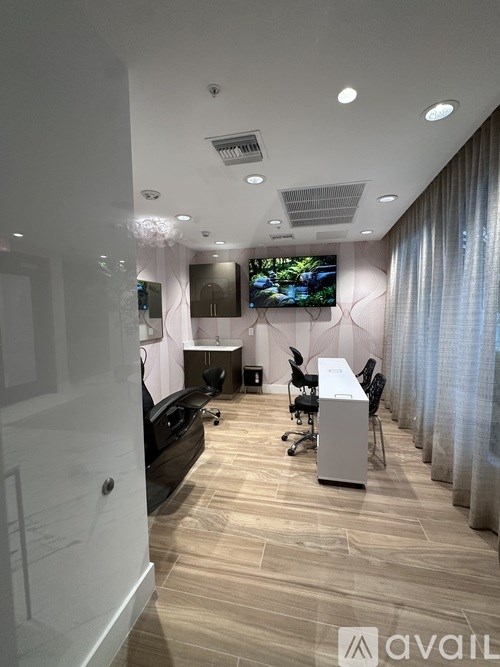 A modern office space with a TV mounted on the wall and a desk with a computer.