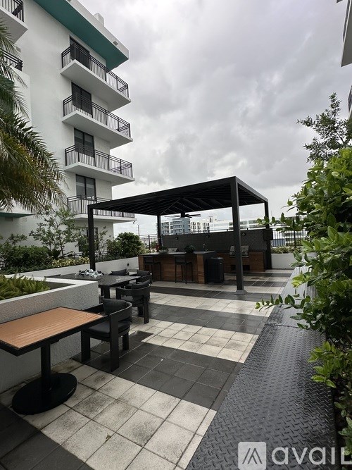 A patio with a table and chairs under a black umbrella.