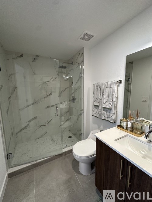 A bathroom with a marble shower and a white toilet.
