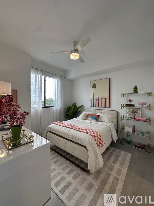 A bedroom with a bed, a fan, and a plant.