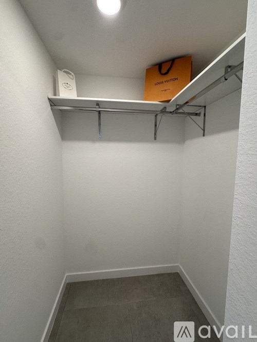 A small closet with a shelf and a Louis Vuitton bag on top.