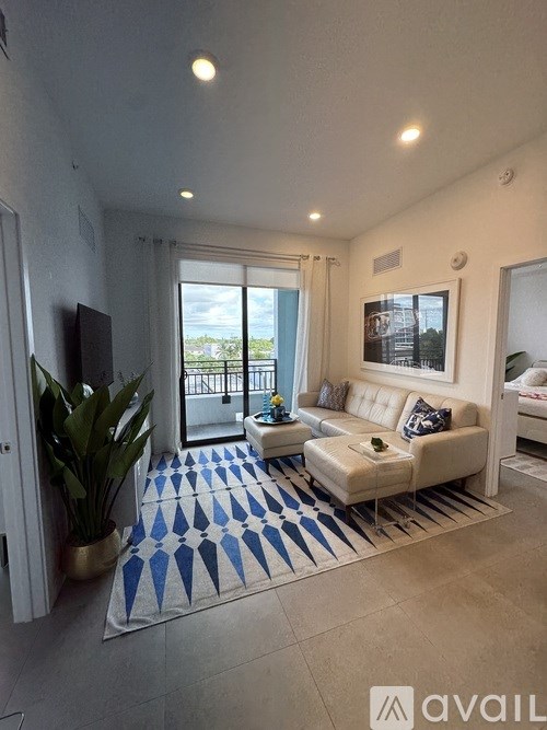 A living room with a white couch and a blue and white rug.