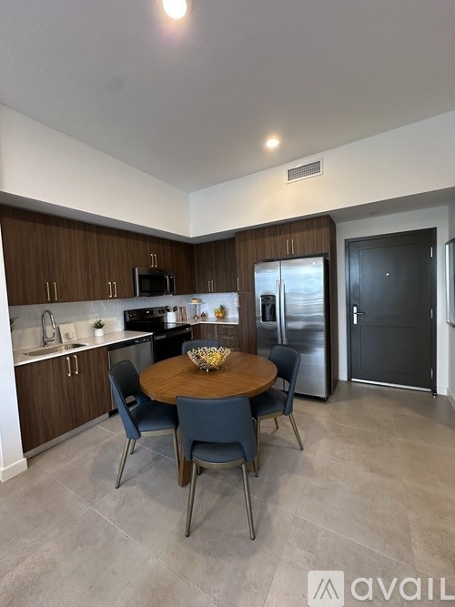 A kitchen with a table and chairs in front of a refrigerator.