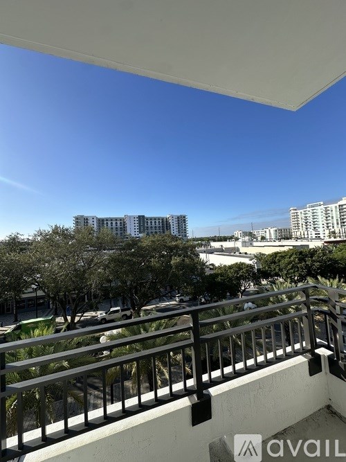 A balcony with a metal railing overlooks a cityscape with buildings and trees.