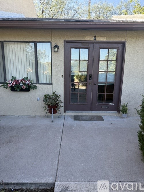 A house number 8 with a grey door and a window with flowers.