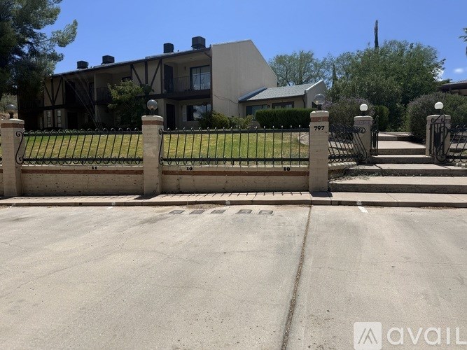 A house with a black gate and a sign that says "AVAIL" in front of it.
