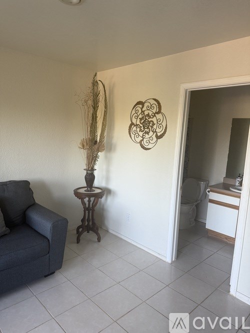 A living room with a grey couch and a table with a plant on it.