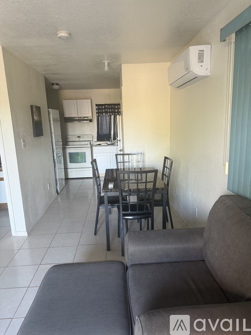 A living room with a grey couch and a dining table with chairs.