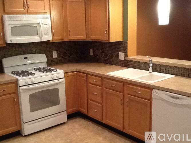 A kitchen with a white stove and wooden cabinets.