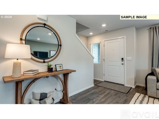 A room with a round mirror on the wall and a wooden table with a lamp and a book on it.