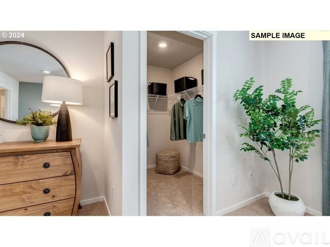 A room with a wooden dresser, a mirror, a potted plant, and a closet with clothes hanging.