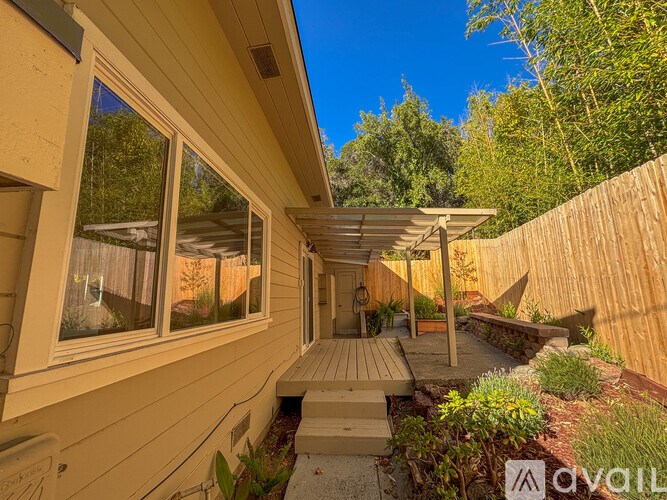 A sunny day at a wooden house with a patio and a garden.