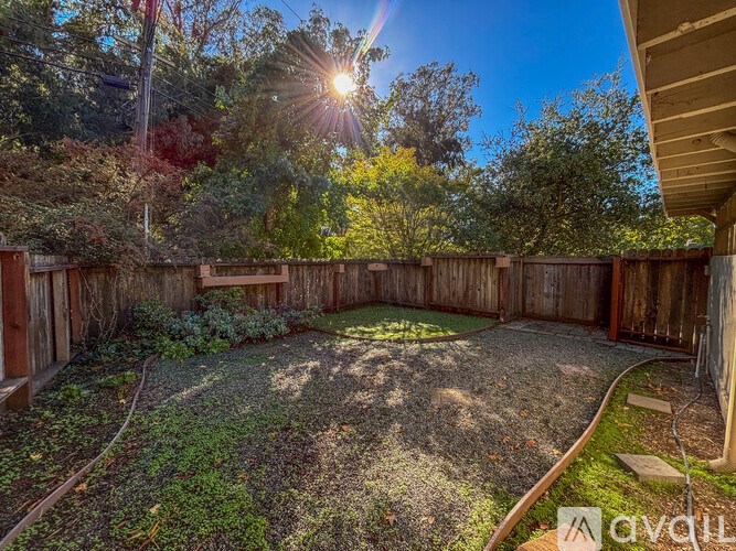 A backyard with a wooden fence and a gravel area.