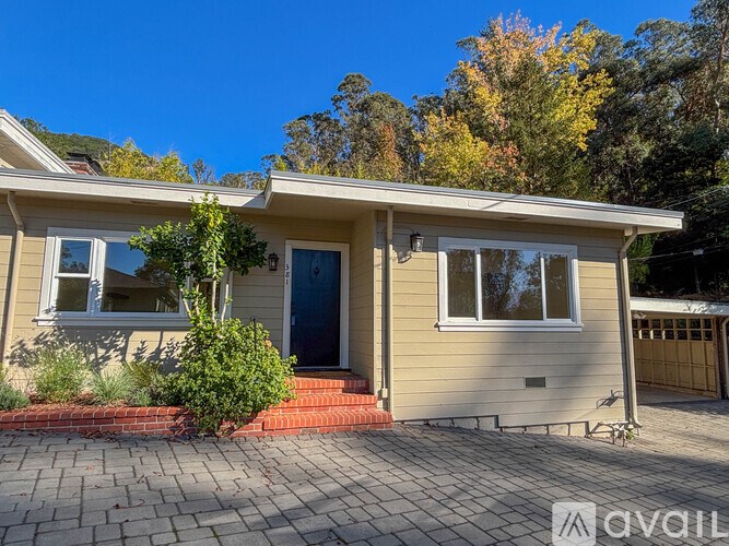 A house with a blue door and windows is surrounded by a brick pathway.