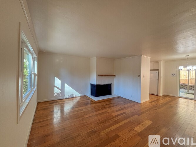 A spacious living room with wooden floors and a fireplace.