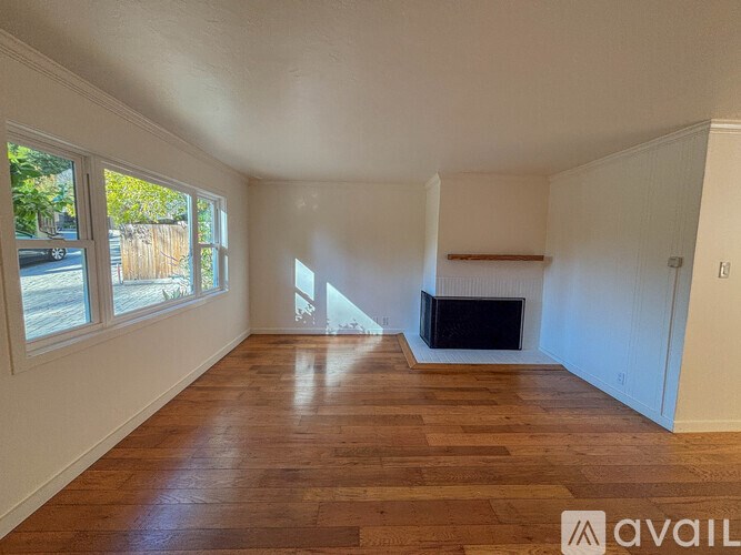 A spacious living room with a fireplace and wooden floors.