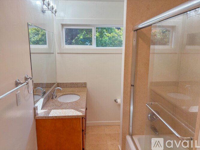 A bathroom with a sink, mirror, and shower.