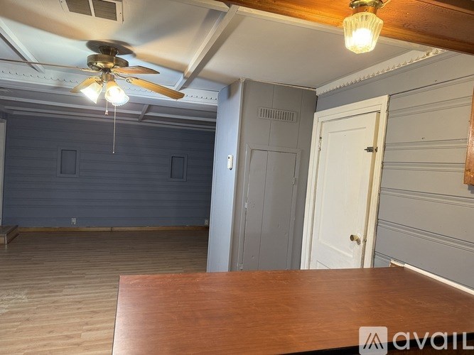 A room with a ceiling fan and a wooden table.