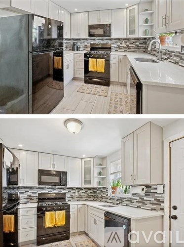 A modern kitchen with white cabinets and black appliances.
